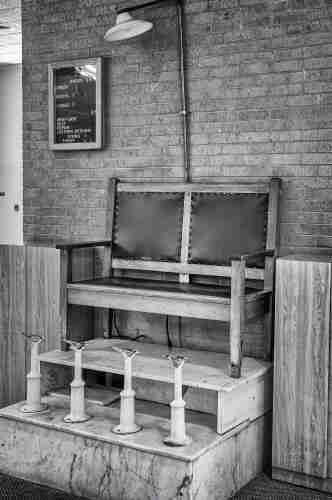 Two spot shoe shine stand in railroad station in Dallas. A sign with prices for different services is posted on the wall nearby.
