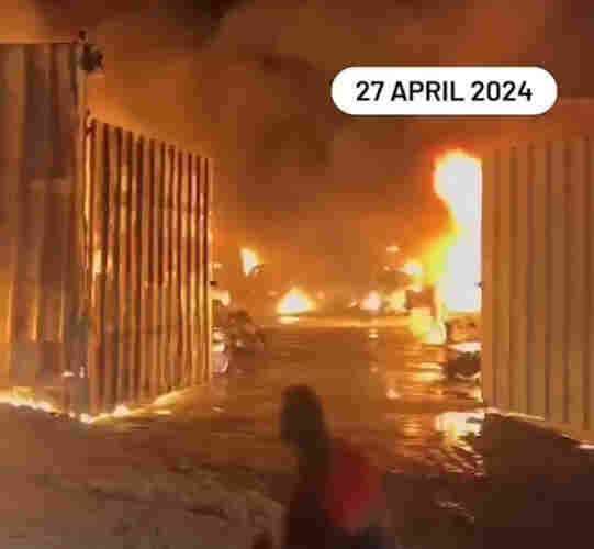Image showing the open front gates of a warehouse which is ablaze, dated 27th April.