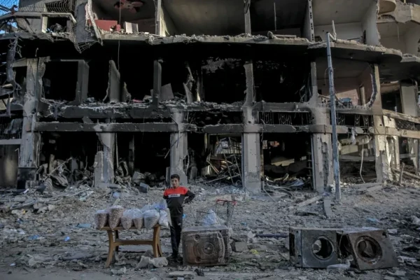A boy waits for customers in front of a building destroyed by Israeli bombardment in Gaza City on Sunday [AFP]