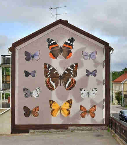 Streetartwall. A huge mural of impressive, realistic butterflies in various colors and patterns has been sprayed on the outside wall of a two-story apartment building. 3 large butterflies in the middle and 8 smaller ones around them.
Info:
1A. Phengaris arion arion 
1B. Scolitantides orion 
1C. Pontia edusa edusa 
1D. Lasiommata megera 
2A. Vanessa Atalanta 
2B. Limenitis populi
2C. Colias crochus
3A. Phengaris arion arion
3B. Scolitantides orion (?)
3C. Pontia edusa edusa
4D. Lasiommata megera