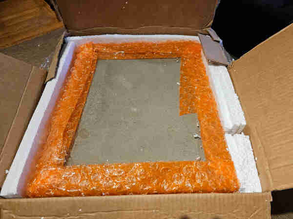 Styrofoam removed from box to partially reveal a really dirty beige metal case of some sort. 