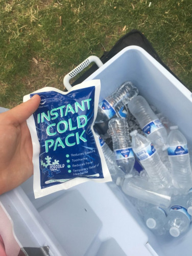 A photo of an instant cold pack being held above a cooler full of cold water