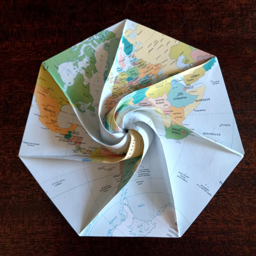 7-sided origami model with curved and straight creases, folded from a stereographic projection of the western hemisphere.