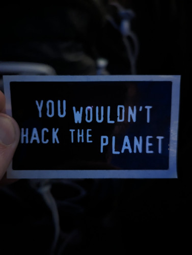 A sticker reading "You wouldn't hack the planet" in the style of "You wouldn't download a car"