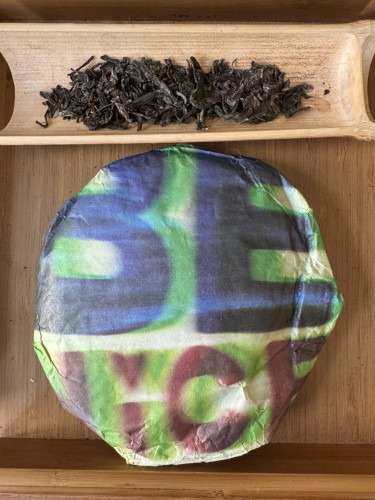 Puerh tea cake in wrapper and dry tea leaves