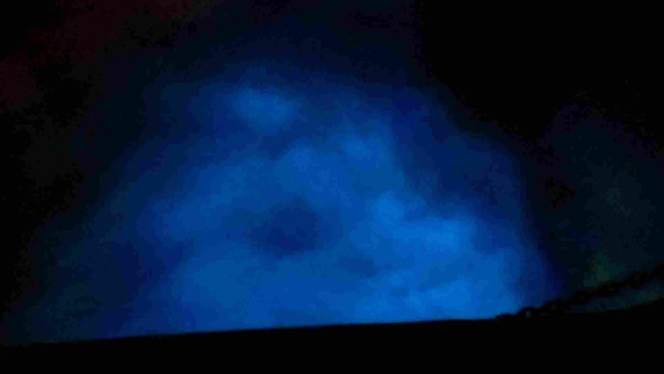 Bow wake glowing bright blue with a faint green patch ahead of it. The chains are almost visible in the silouhette. 