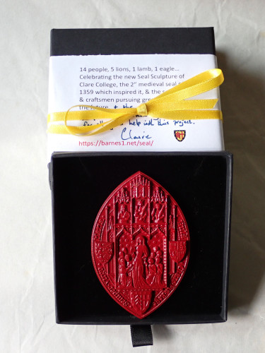Red resin replica of the Seal Sculpture in a presentation box, with description & thank you note & ribbon - red, yellow & black, the heraldic colours of Clare College, as shown in the shield. 