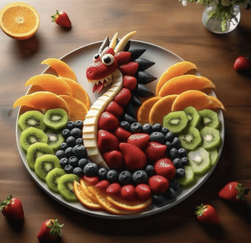 Strawberries, blueberries, orange segments, and kiwi slices arranged on a plate to form a dragon.