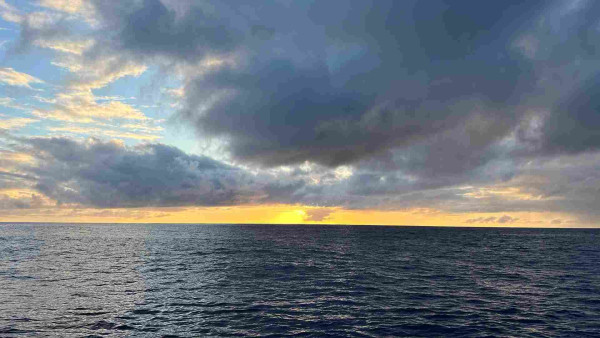 Sunset with dark clouds above a still sea. 