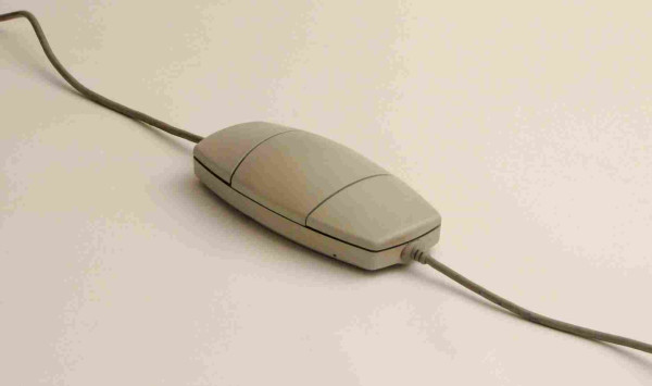 A photo of a beige Apple two-button mouse, which goes all the way and has two cables too. It's kind of rounded off, teardrop-shaped, and the buttons allow two-handed use.
