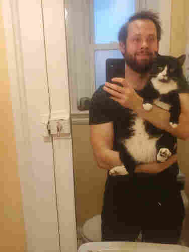 Mirror selfie of me holding Fishy, my big tuxedo cat.