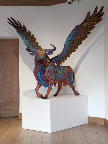 My photo of a bull statue that has eagle wings and is highly decorated with colours and patterns that is on a plinth