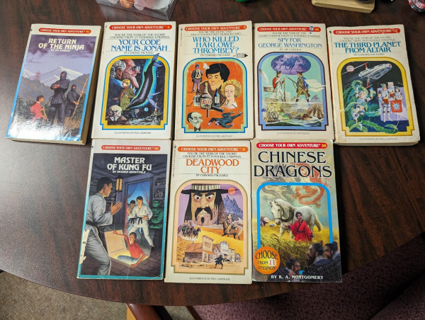 8 Choose Your Own Adventure books laid out on a table: Return of the Ninja, Your Code Name is Jonah, Who Killed Harlowe Thrombey, Spy for George Washington, The Third Planet from Altair, Master of Kung Fu, Deadwood City, and Chinese Dragons. They are all brilliant and wonderful. 