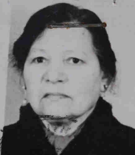 Photo for documents of an elderly woman. She has dark hair and a black coat. 
