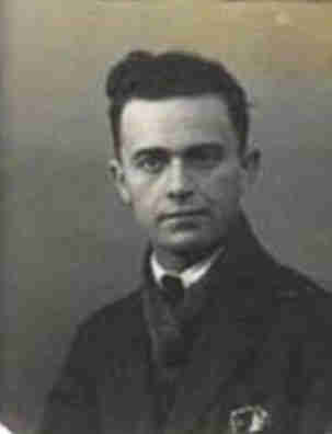 A handsom man portrait photo. He wears a coat, scarf and a tie. He has short dark hair.