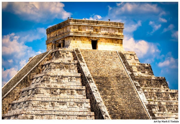 Color digital photograph of the top of the main Mayan pyramid at Chichen Itza with bright sunlight and blue skies mixed with clouds as a backdrop. 