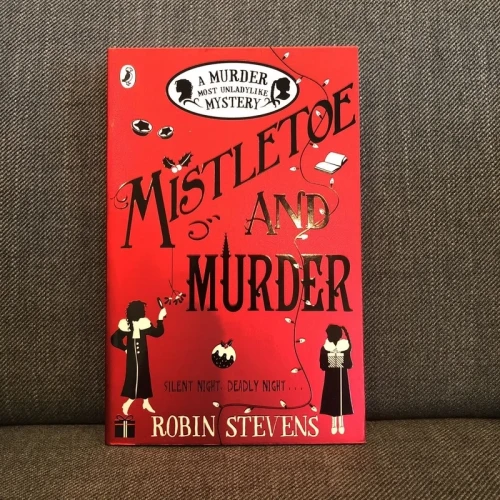 The cover of Mistletoe and Murder by Robin Stevens. A red background. Black font. The silhouettes of two girls, as they investigate a murder.
