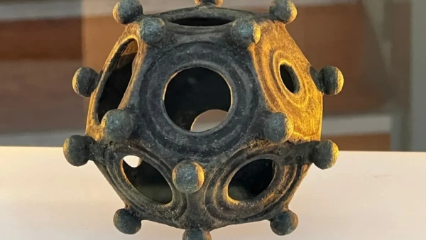 A roman dodecahedron: it's a regular 12 sided shape with little round balls at the corners and holes of differing sizes in each face.