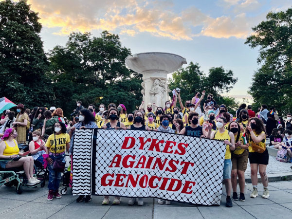 Protestors wearing masks and holding a banner that reads “DYKES AGAINST GENOCIDE”