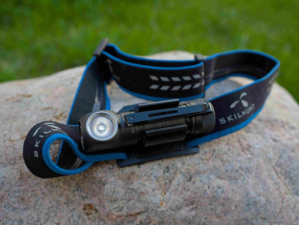 An activated Skilhunt H150 headlamp sits on a rock