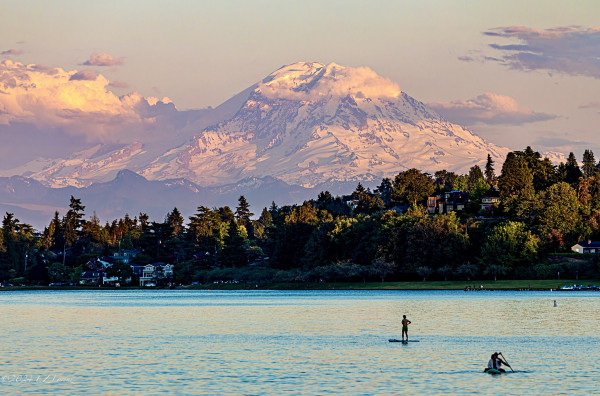 Tahoma towering over Lake Washington at sunset on the first evening of Summer. 
There’s a paddlepoarder and a kayak on the blue lake. 