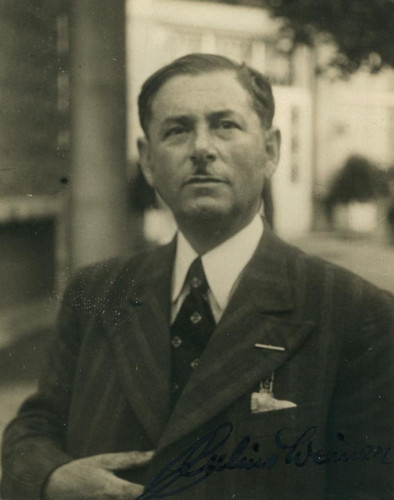 A portrait of a man in a striped suit standing in the street. 