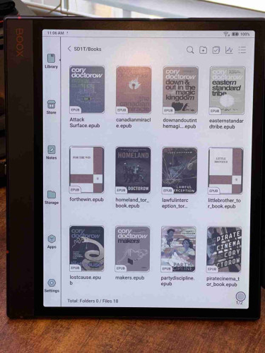 Photo of a Boox Note Air 3C e-reader showing the "Library" view, with 12 book covers of books by Cory Doctorow displayed.