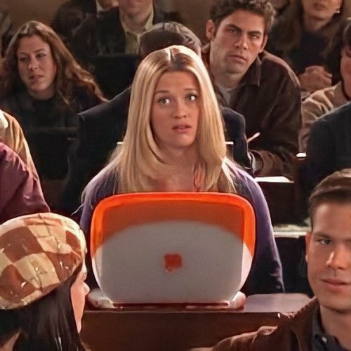 Still from movie "Legally Blonde" with Elke sitting in a lecture with her cheery orange and white Mac laptop