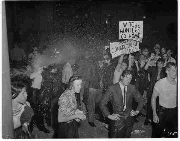 Soaked students at San Francisco City Hall, May 13, 1960, during anti-HUAC protests. The sign says, "Witch Hunters Go Home!"