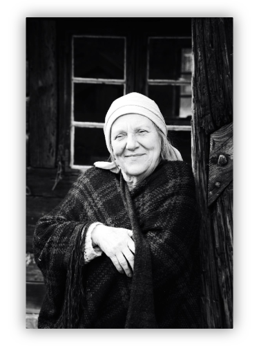 Portrait of an old lady in front of a country house.