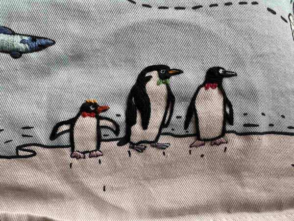 Three small embroidered penguins. The are all wearing small bow ties 