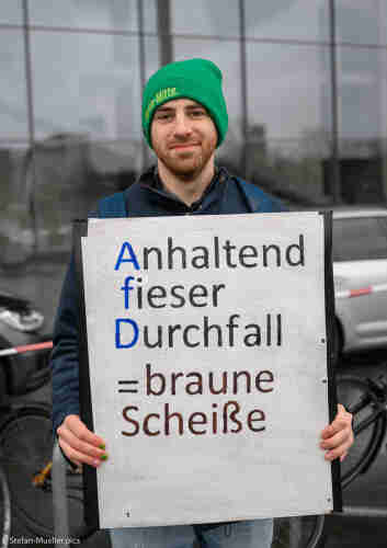 Teilnehmer der Demo „Wir sind die Brandmauer“ gegen Faschismus und die AfD mit Schild: „Anhaltend fieser Durchfall = braune Scheiße“, Berlin, 03.02.2024