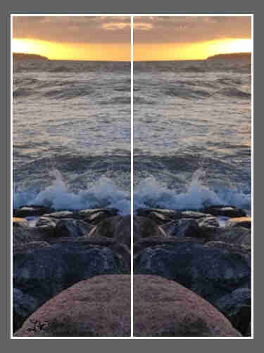 Ein gespiegeltes Foto vom Sonnenuntergang am Warnemünder Strand. Im Vordergrund schlagen die Wellen auf große Steine.