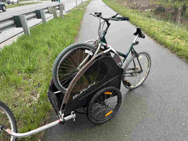 Old cheap hybrid bike I found on the side of the highway with a flat tire, front wheel slung over the crossbar of my kid trailer so I can haul it home 