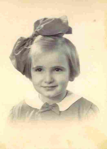 A portrait ID photo of a young girl with a huge bow at the top of her head. She has blonde hair reaching to her ears. 