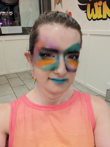 Hazel looks at the camera while wearing extremely abstract makeup that looks like a smudge of colors
