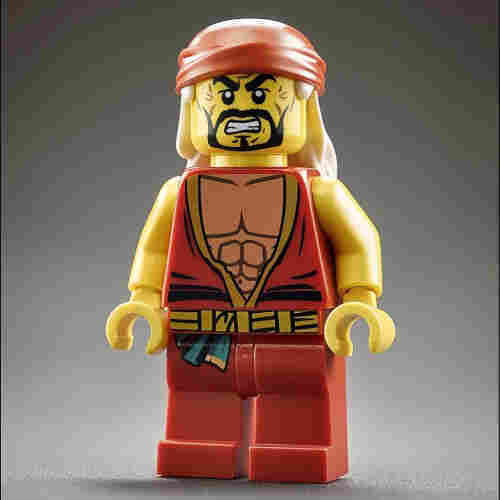 A LEGO minifigure that strongly resembles the wrestler Hulk Hogan. The figure has a muscular appearance, with a yellow skin tone. It features a prominent black beard and mustache combo on a stern, wrinkled face. The minifigure is wearing a red tank top with a deep V-neck showcasing a muscular chest, and a red bandana with a yellow outline on its head, which is characteristic of Hulk Hogan’s iconic look. The figure also has yellow arms, red pants, and a yellow belt with a black center. Its hands are in the standard C-shape grip of LEGO figures, and it stands against a grey background.