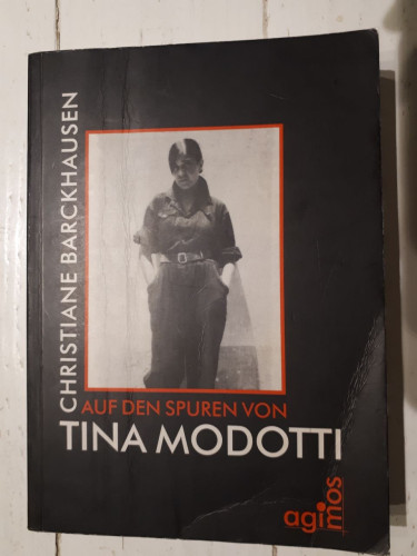 Ein etwas abgegriffenes Buch. Der Einband ist schwarz mit einem Schwarzweißfoto einer Frau, Tina Modotti, in einem Hosenanzug. Unter dem Foto steht der Titel: "Auf den Spuren von Tina Modotti". Der Name der Autorin, Christiane Barckhausen, steht senkrecht neben dem Foto. Der Verlag, Agimos, steht unten rechts auf dem Cover.