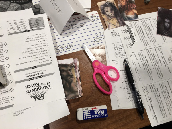 photo of a mess of a table with character sheets, notes, erasers, printed out images from Tony DiTerlizzi's Planescape work, and a pair of safety scissors (for some reason)