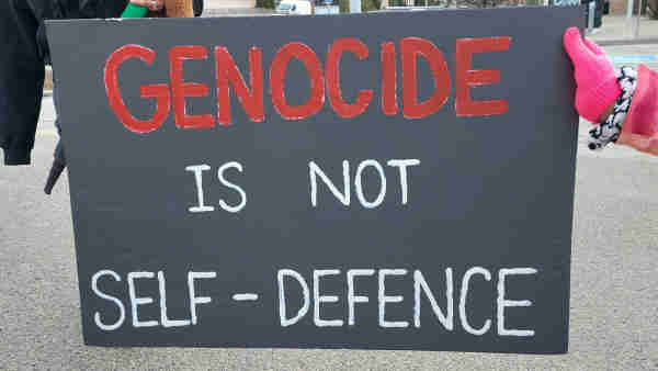 A handmade protest sign on black reads: 

Genocide is not self-defense.