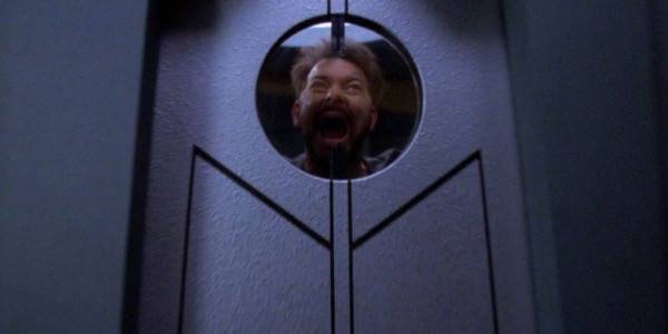 Riker, face framed by window in a secure door in an insane asylum. His hair is mussed. He’s screaming. Presumably about the sad state of health care on that world as he just knows this is going to cost him a lot of latinum. 