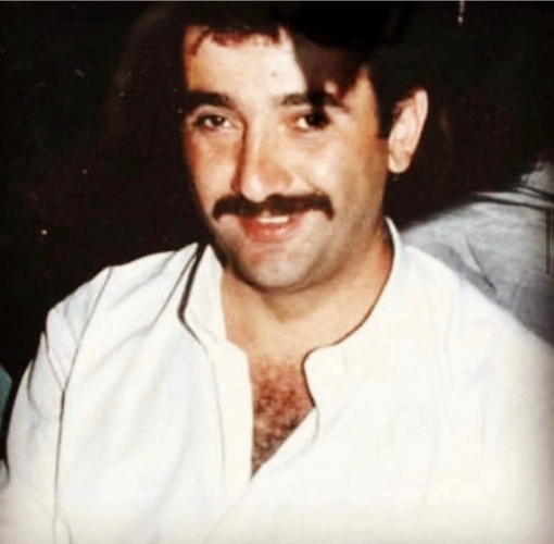 Ein Foto von Theodoros Boulgarides. Er lächelt in die Kamera, trägt einen Schnurrbart, ein offenes weißes Hemd. 