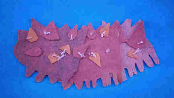 A scrappy brown felt and embroidery floss sea cucumber in three visible segments.