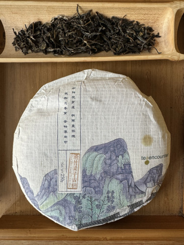 Puerh tea cake in wrapper and dry tea leaves 