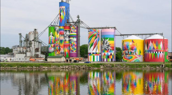 Massive silo complex painted in rainbow colors, with lots of spiky stars, triangles, squares and accents of black and white 