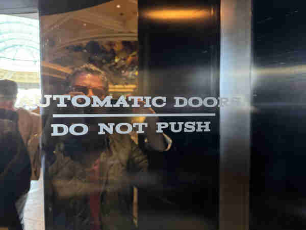 Prominent signage on a glass door reading: AUTOMATIC DOOR DO NOT PUSH