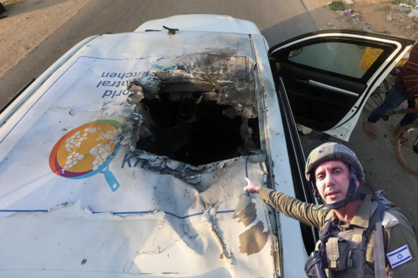 A montage of the destroyed world central kitchen van with the IDF spokesman that turned into a meme after pointing at some sheets of paper as proof of Hamas using Al Shifa hospital as a base, pointing at the destroyed van.