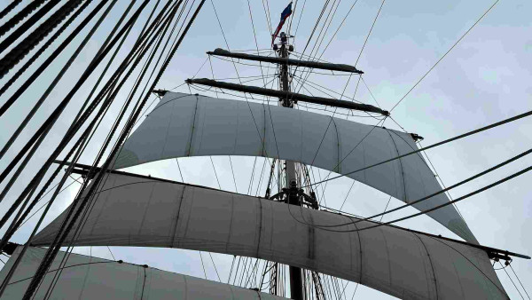 Square sails viewed from the forward deck with the flag on the mast going straight ahead. 