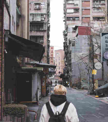 A blonde person walking in the street of Taipei.
