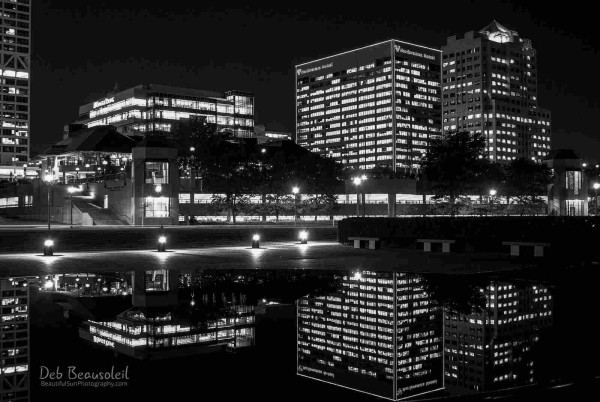 Black and white night photograph of illuminated city buildings reflected in a still pond. Image at:  https://beautifulsunphotography.com/featured/black-and-white-city-reflections-deb-beausoleil.html See more art & blog at: https://beautifulsunphotography.com/ https://debbeautifulsunphotography.com/ https://www.zazzle.com/store/beautifulsun_designs https://debbeausoleil.com